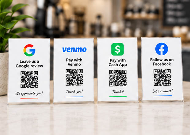 A counter cluttered with separate signs and QR codes for Google, Venmo, Cash App and Facebook